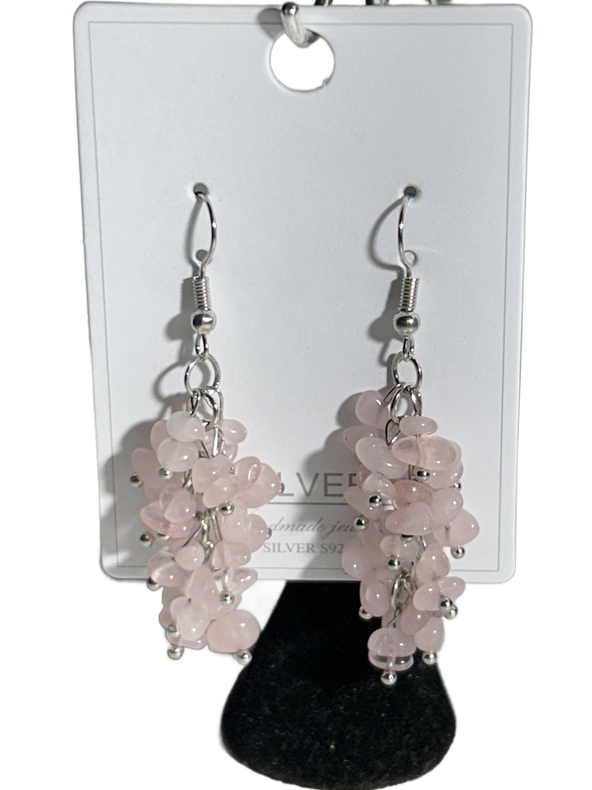 Pink rose quartz bead cluster dangle earrings with silver fishhook wires, displayed on a white card with a black velvet stand against a white background.