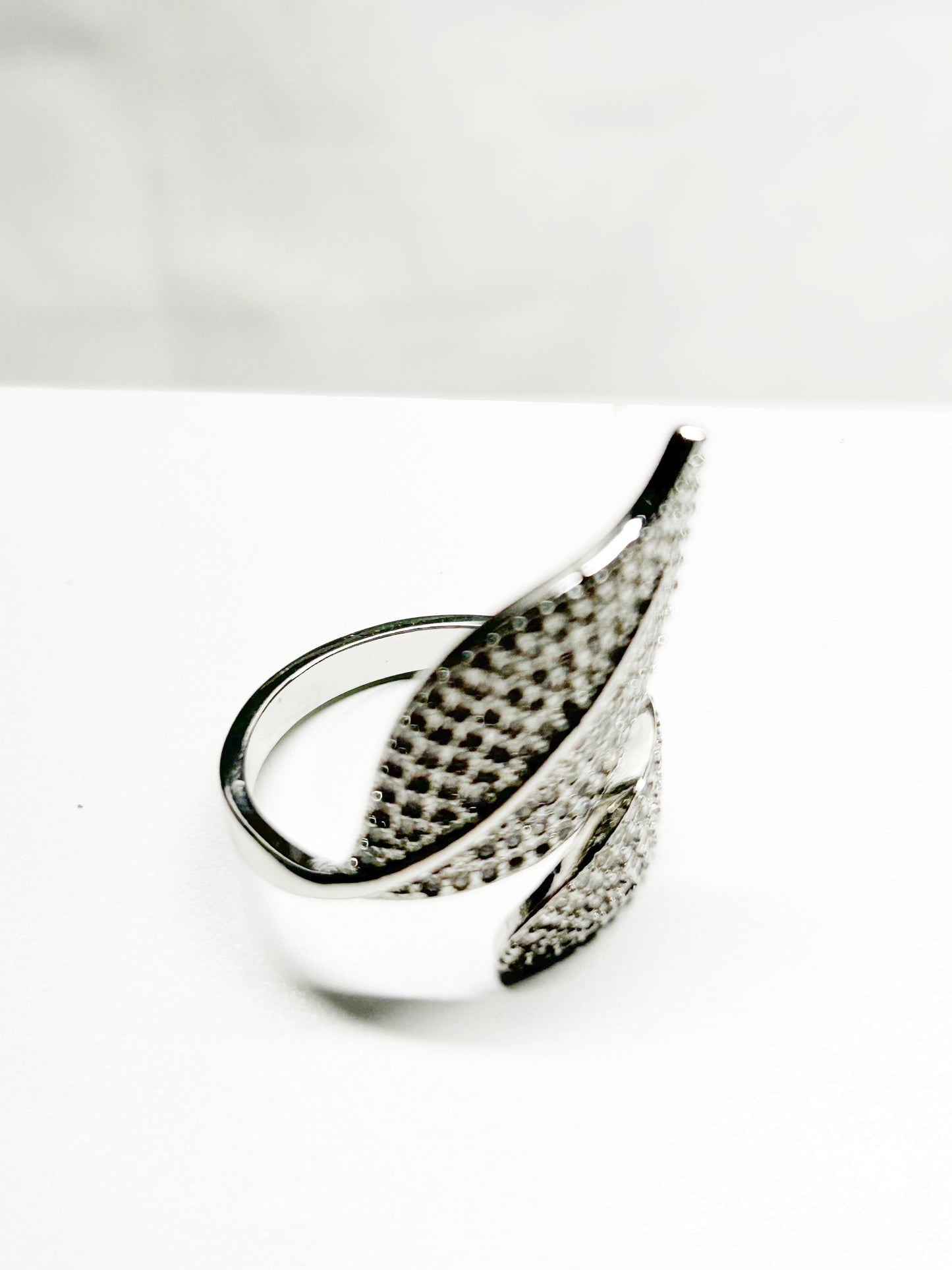 Silver ring with feather design on a white background
