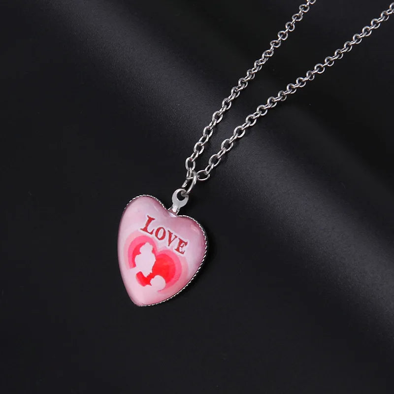 Heart-shaped pendant with 'LOVE' and cartoon design on a chain against a dark background