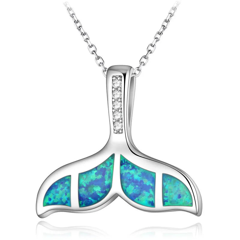 A silver whale tail pendant necklace featuring vibrant blue and green opal inlays, set on a delicate silver chain against a white background.