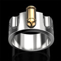 A silver-toned metal ring featuring a cylindrical gold-toned bullet embedded vertically in the center, shown against a solid black background.