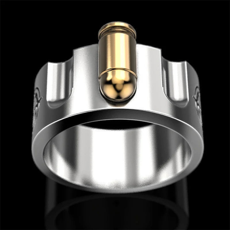 A silver-toned metal ring featuring a cylindrical gold-toned bullet embedded vertically in the center, shown against a solid black background.