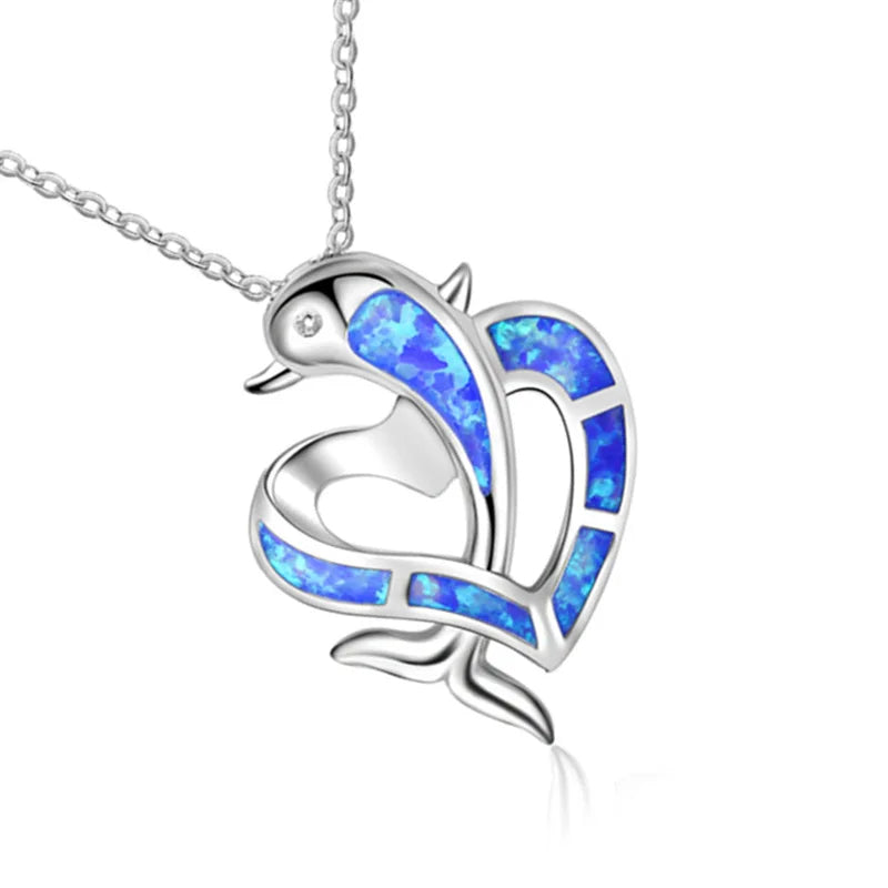 A silver pendant necklace featuring a stylized dolpin design with vibrant blue opal inlay, suspended from a silver chain against a white background.