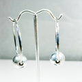 Silver earrings with floating round ball 
on a stand with a plain background