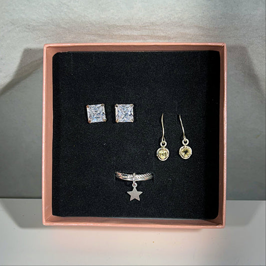 Jewelry set including earrings and a ring in a rose gold box on a gray background