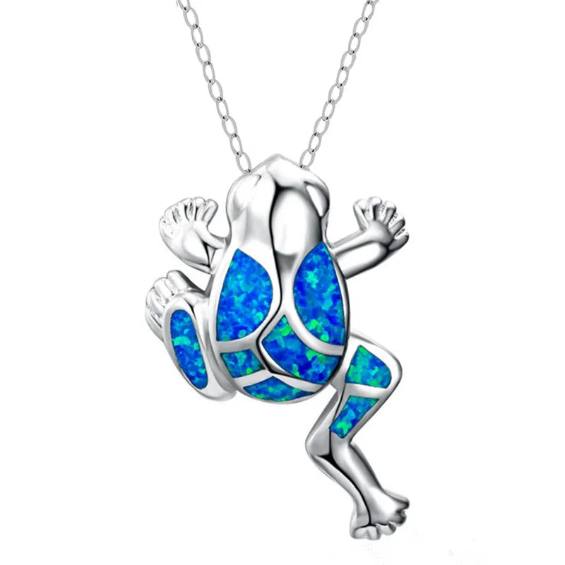 A silver frog pendant necklace featuring vibrant blue opal inlay on its back and legs, suspended from a silver chain against a plain white background.