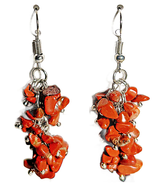 A pair of dangling earrings made from irregular orange-red coral-like stones set in silver-tone metal with fishhook backings, shown on a plain white background.