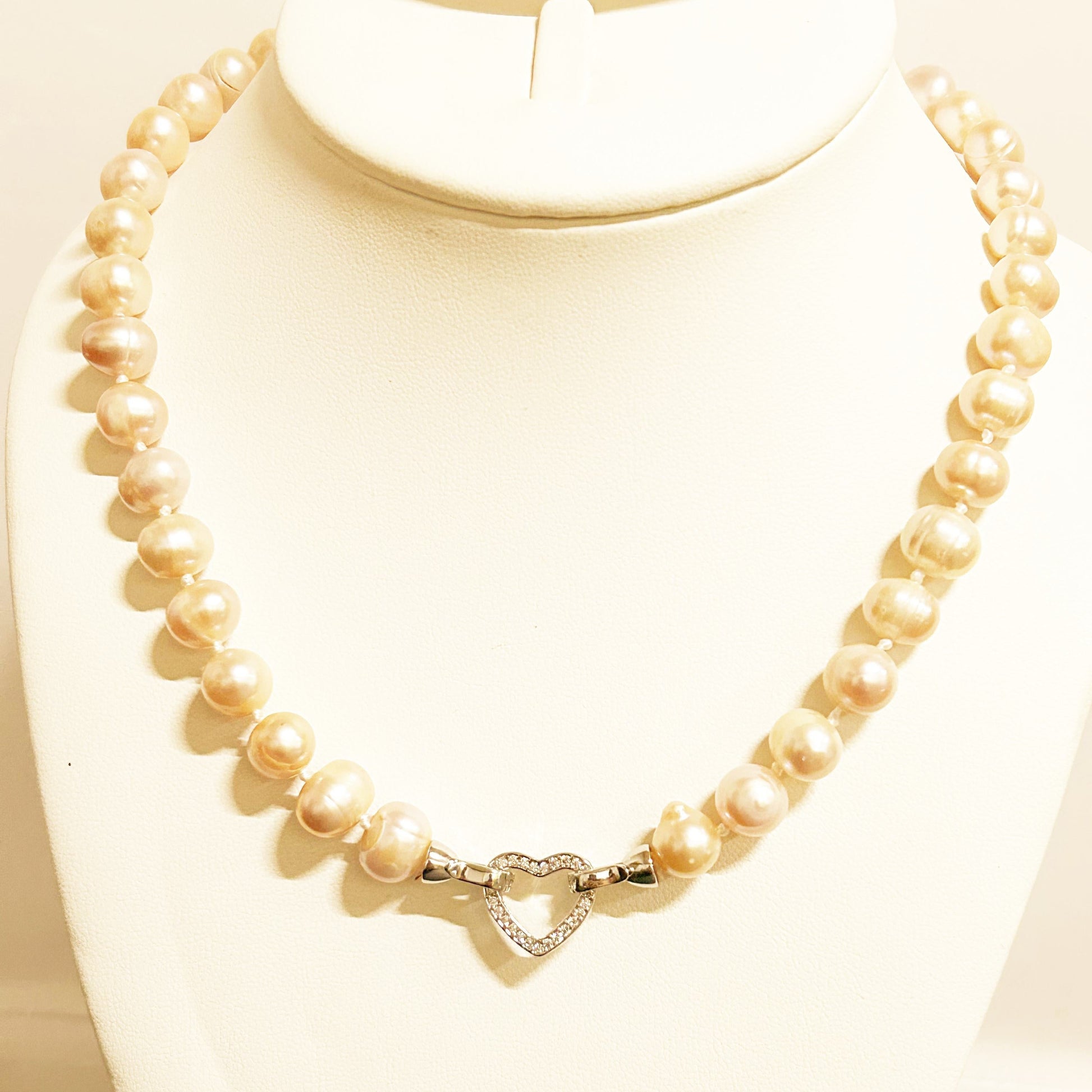 Pearl necklace with a heart-shaped clasp on a mannequin bust.
