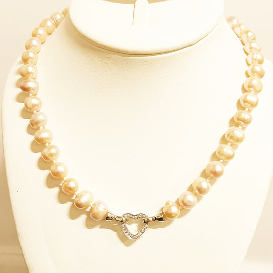 Pearl necklace with a heart-shaped clasp on a mannequin bust.