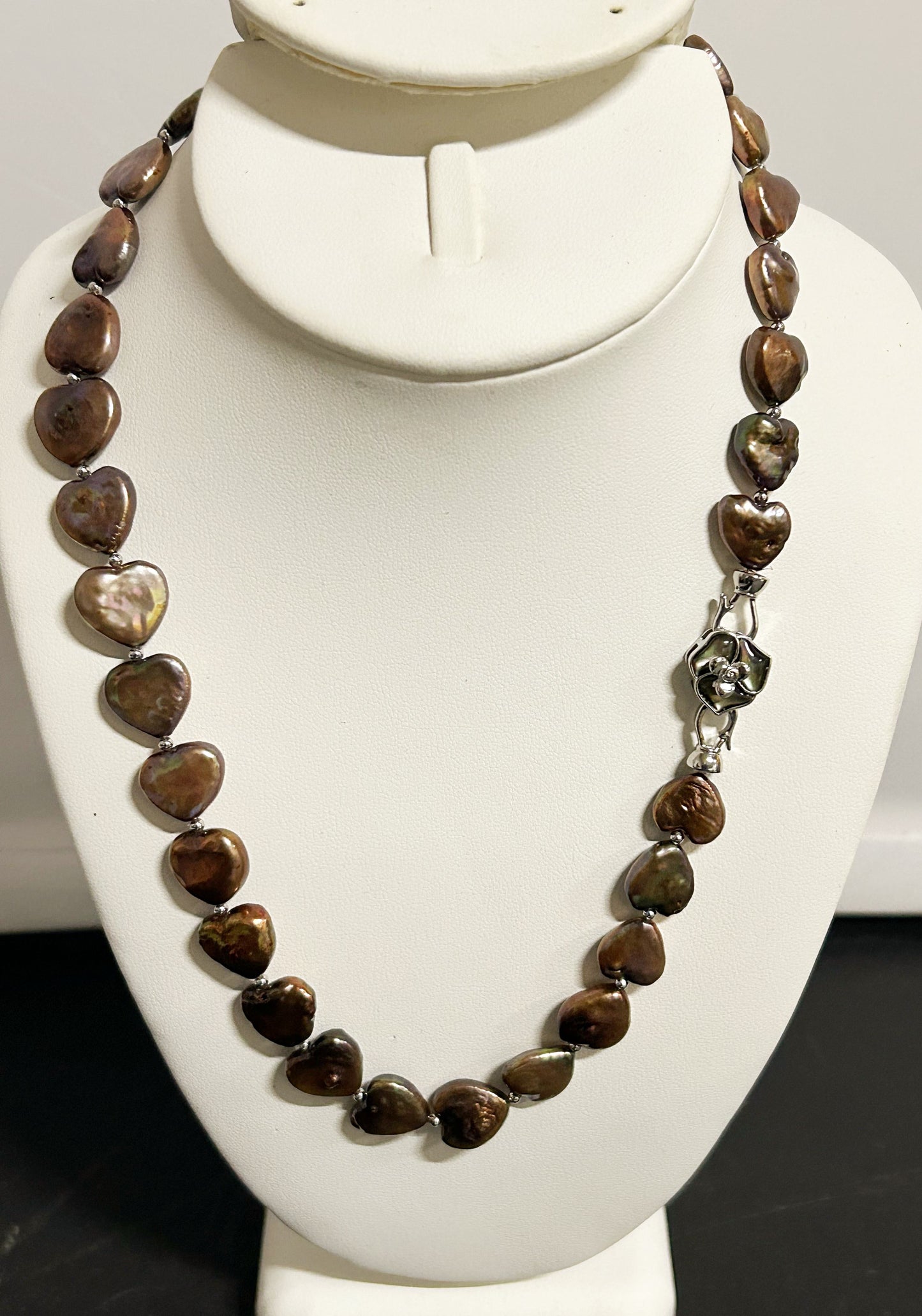 Necklace with heart-shaped brown stones on a white mannequin bust.