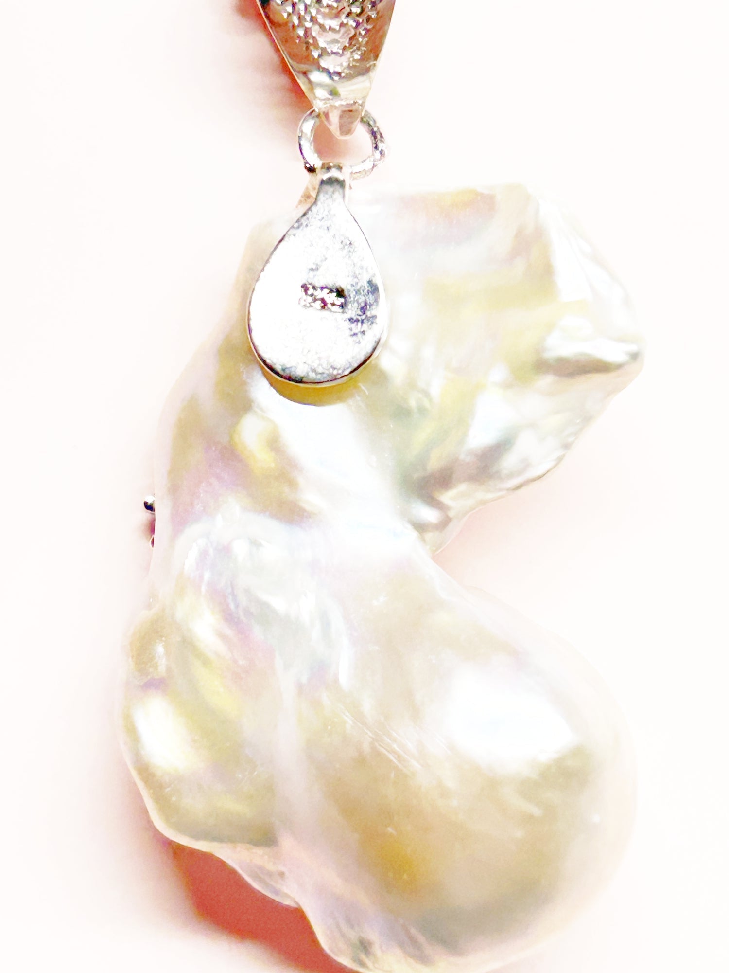 Cat-shaped pearl pendant with a clear gemstone on a white background