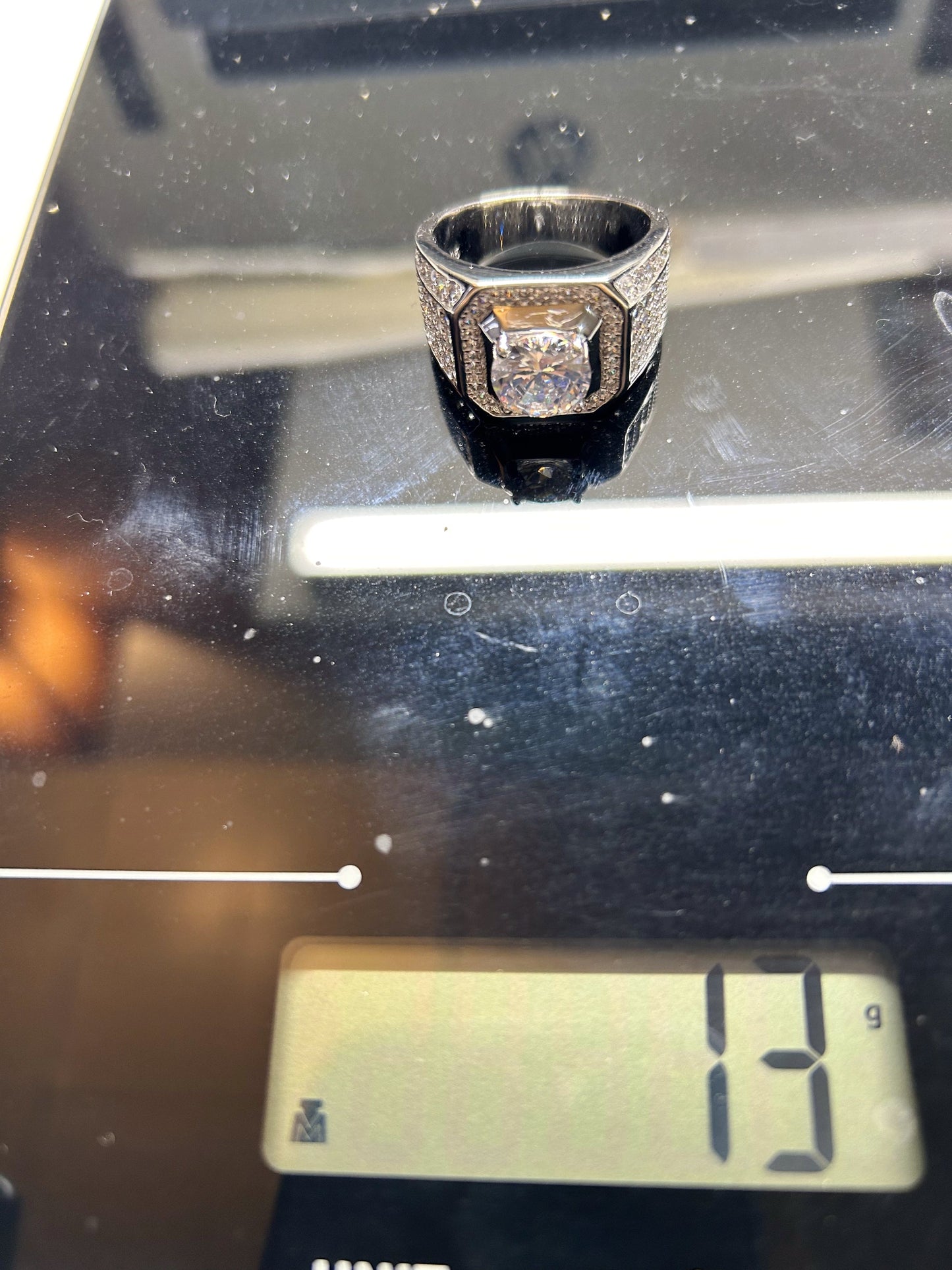 Silver ring with a diamond on a digital scale displaying 13 grams.