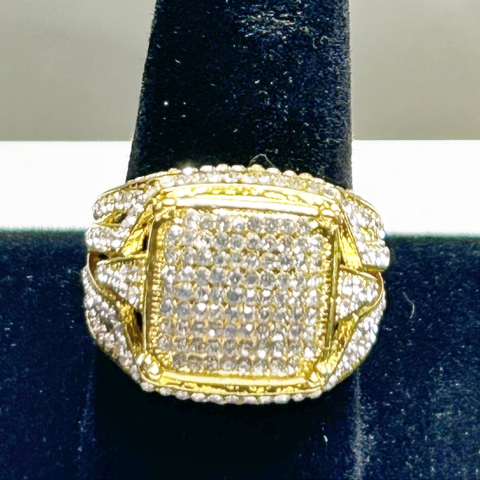 Gold and diamond ring on a black velvet stand with a white background