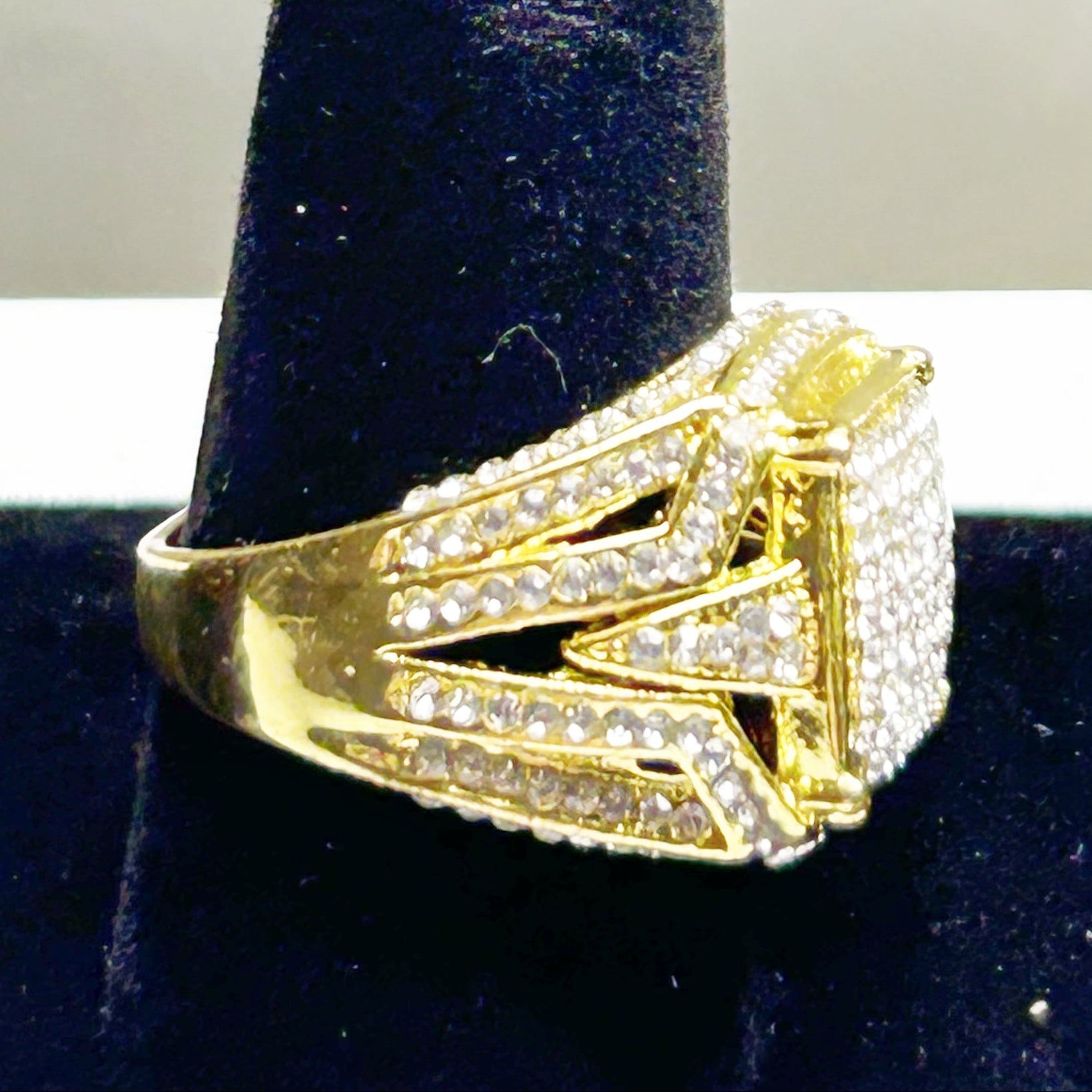 Gold ring with diamond accents on a black stand