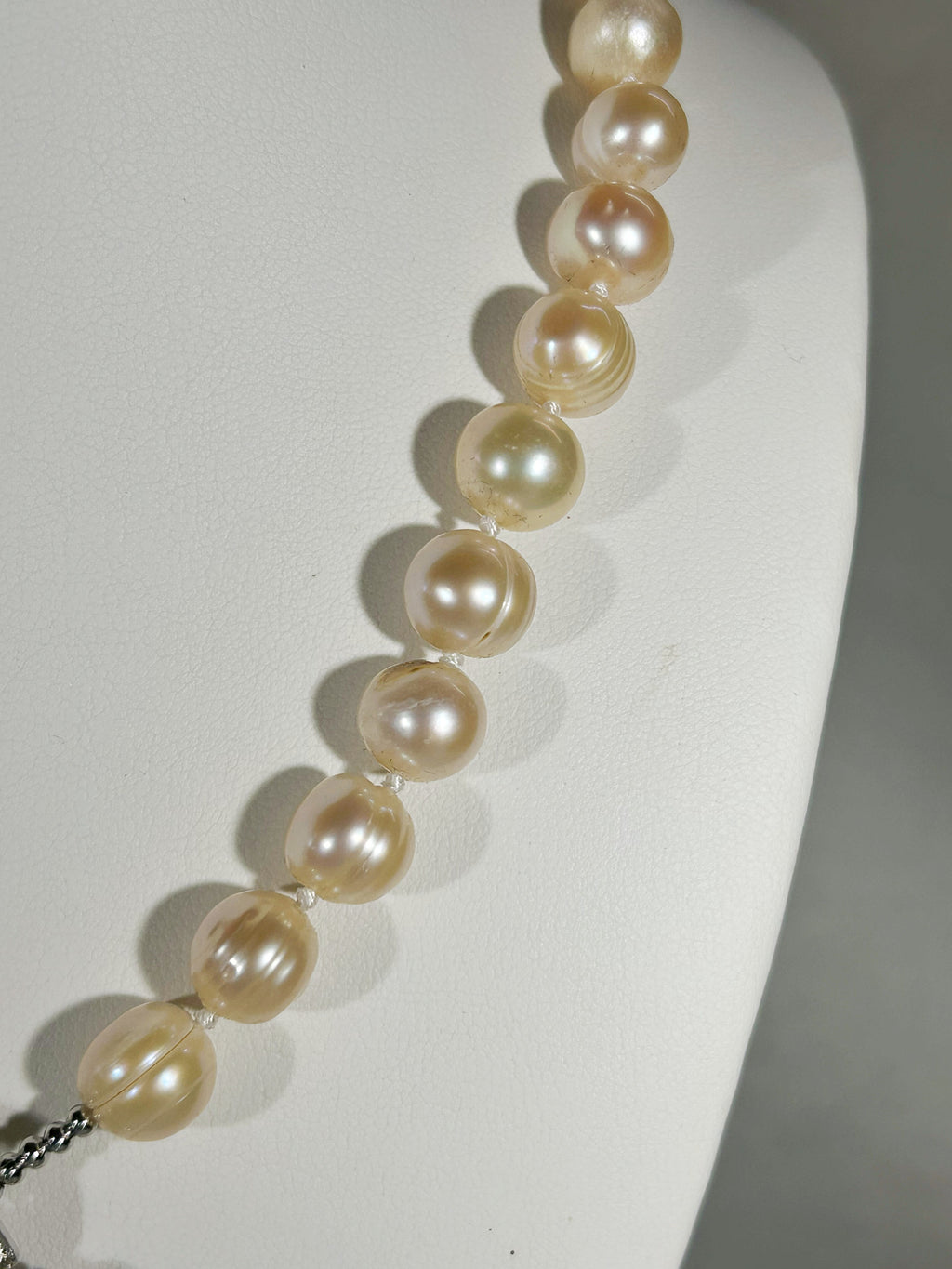 Pearl necklace on a white stand with a neutral background