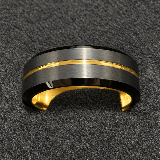 A black and gold ring with a brushed black outer band and a polished gold inlay, resting on a textured black felt surface.