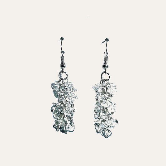 A pair of silver dangle earrings with organic, fluid, cloud-like textured drops, shown against a solid off-white background.
