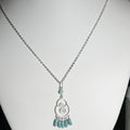 Necklace with a silver pendant and turquoise beads on a white mannequin.