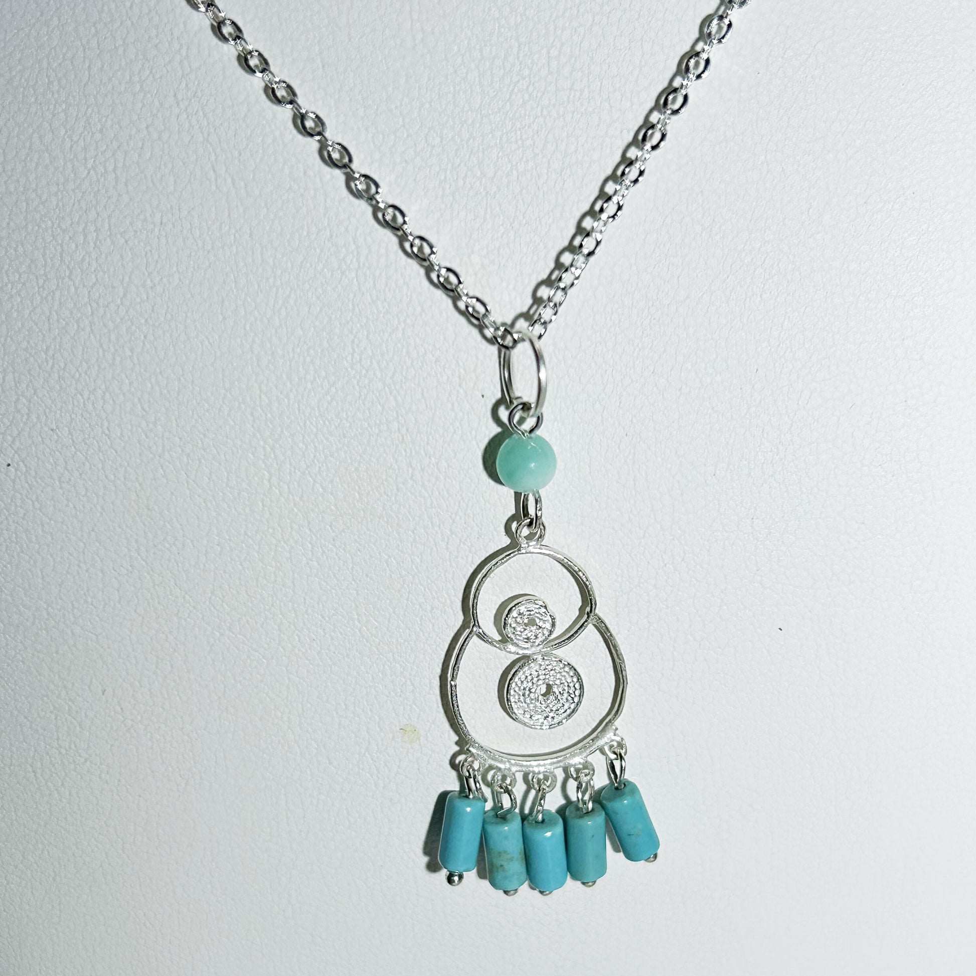 Necklace with turquoise beads and silver chain on a light gray background