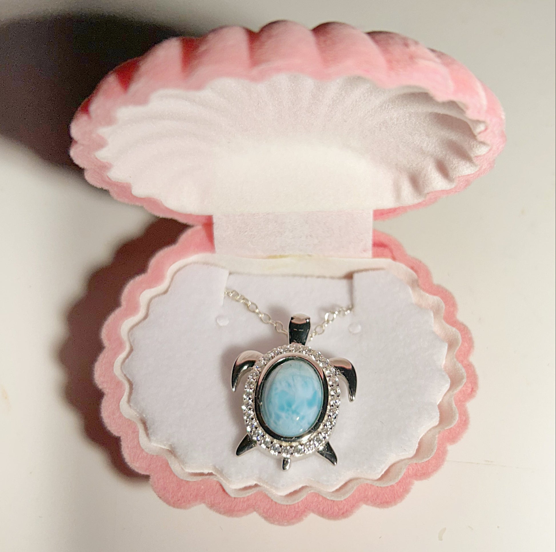 Turtle-shaped pendant with blue stone in a pink shell box